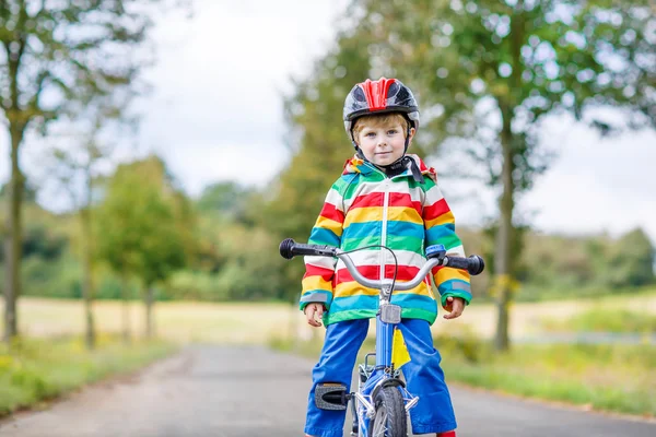 Kid boy in helmet riding his first bike, outdoors — Stock Photo, Image