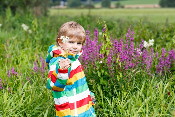 Little blond boy with lot of wild flowers — Stock Photo, Image