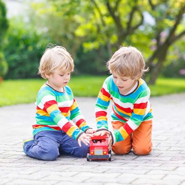 Twee kleine vrienden spelen met rode bus van de school — Stockfoto