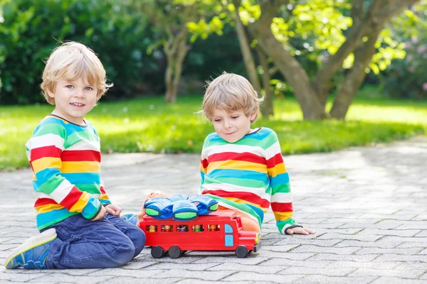 Två syskon, kid pojkar leker med röda skolbuss — Stockfoto