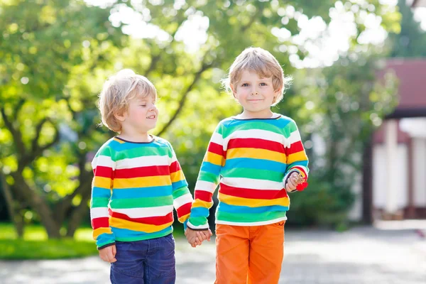 Zwei kleine Brüder Kinder in bunten Kleidern zu Fuß Hand i — Stockfoto