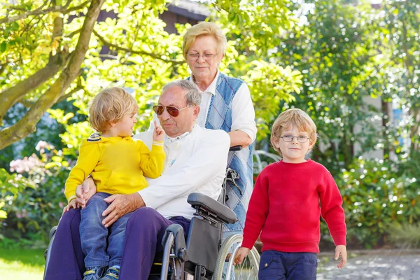 Two little kid boys, their grandmother and grandfather in wheelc — Stock Photo, Image