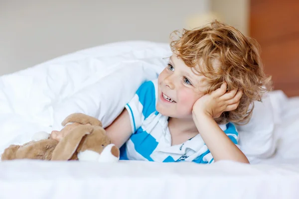 Adorable kid boy after sleeping in his white bed with toy — Stock Photo, Image