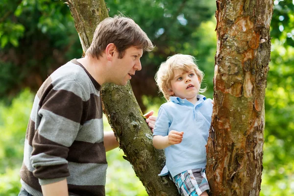 Cute little kid boy enjoying climbing on tree with father, outdo — Stock Photo, Image