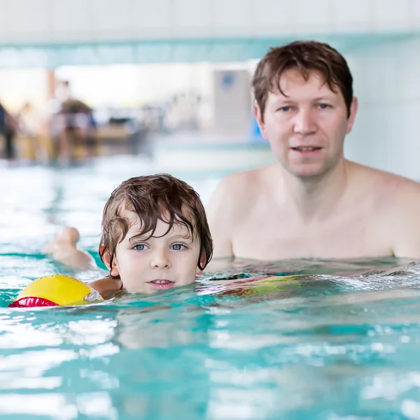 Young dad teaching his little son to swim indoors — Stock Photo, Image