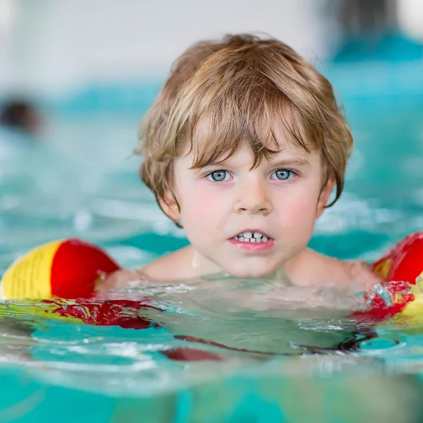 Happy little kid boy having fun in an swimming pool. Active happy