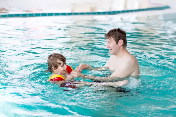 Little kid boy and his father swimming in an indoor pool — Zdjęcie stockowe