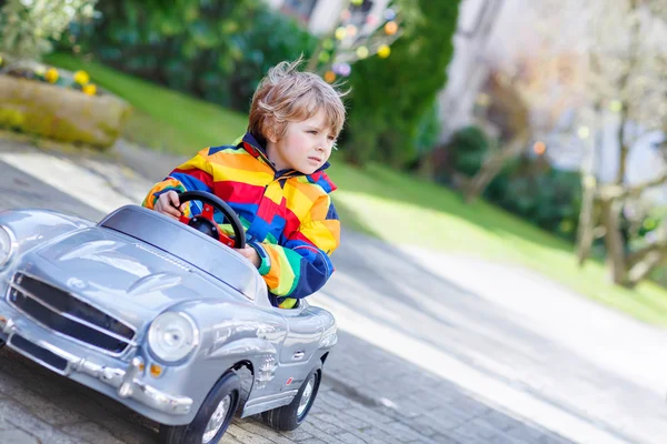 Pequeño niño preescolar conduciendo un gran juguete viejo coche vintage, al aire libre —  Fotos de Stock