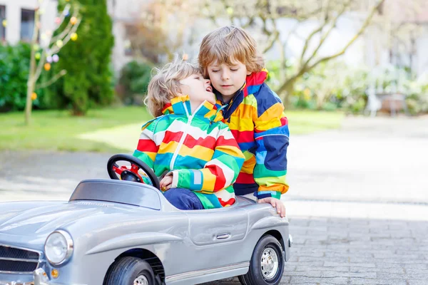 Deux garçons heureux frères et sœurs jouant avec une grande vieille voiture jouet — Photo