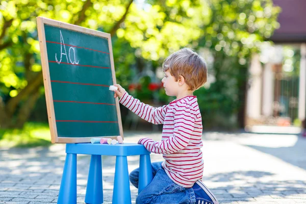 Petit garçon au tableau noir apprenant à écrire — Photo