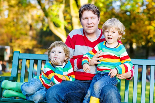 Dois meninos e um jovem pai sentados juntos, outono, o — Fotografia de Stock