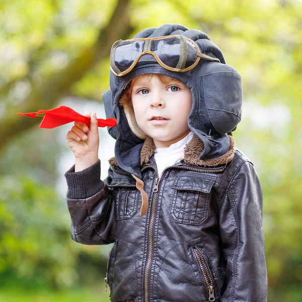 Garçon heureux en casque de pilote jouant avec un avion jouet — Photo