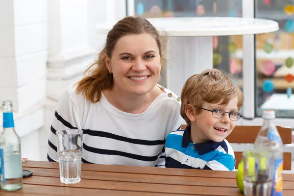 Menino com óculos e sua mãe desfrutando de bebidas — Fotografia de Stock