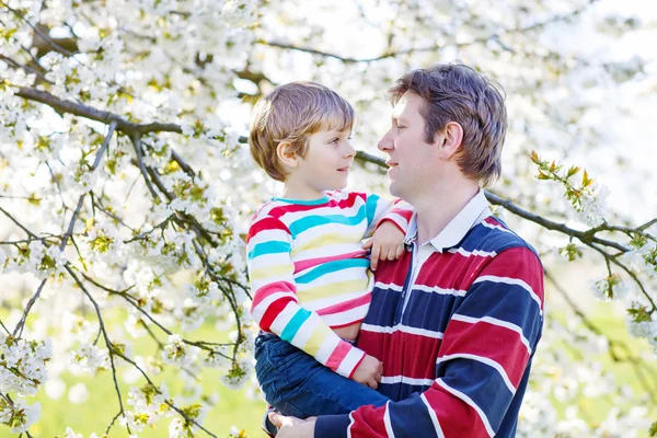 Unga far och Lille unge pojken i blommande trädgård — Stockfoto