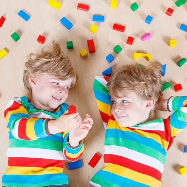 Two little children playing with colorful wooden blocks indoor — Zdjęcie stockowe