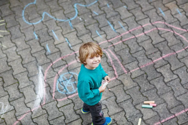 Pequeño niño rubio pintando con tiza de colores al aire libre — Foto de Stock