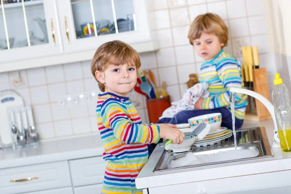 Due piccoli ragazzi biondi lavano i piatti in cucina domestica — Foto Stock