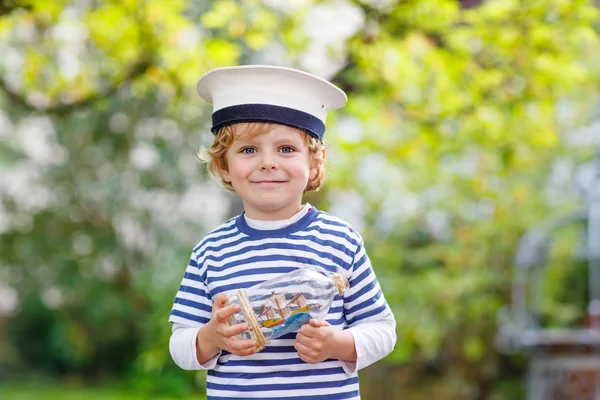 Gelukkig jong geitje in schipper uniforme spelen met speelgoed schip — Stockfoto