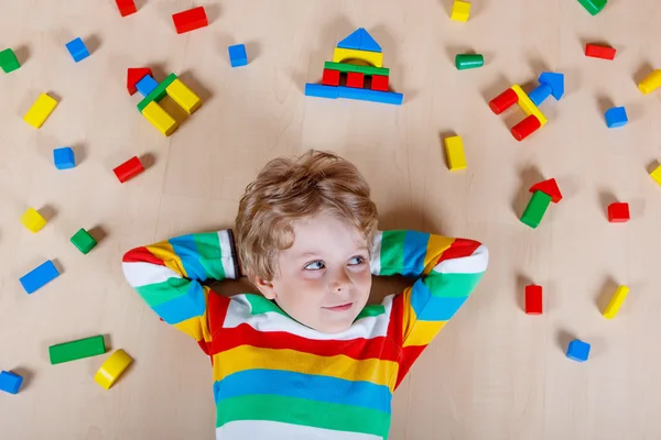 Pequeño niño rubio jugando con bloques de madera de colores en interiores — Foto de Stock