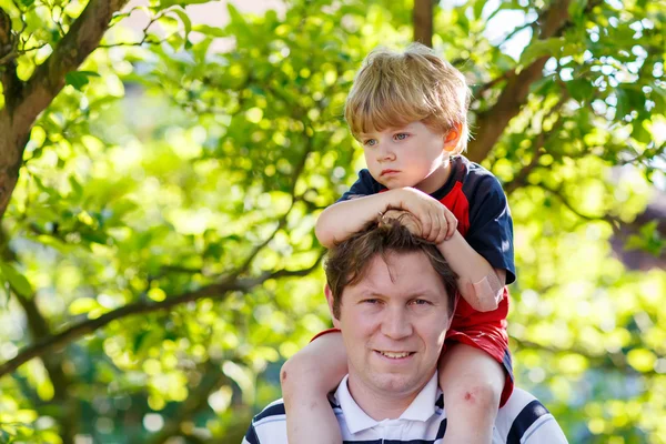 Father carrying child on his shoulders in the park Royalty Free Stock Photos
