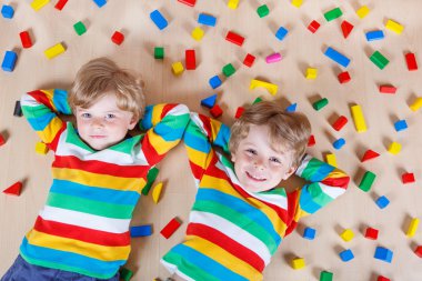 Two little children playing with colorful wooden blocks indoor
