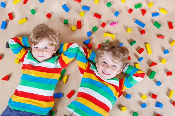 Two little children playing with colorful wooden blocks indoor