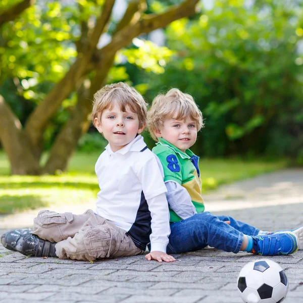 Two little sibling boys playing soccer and football — Stock Photo, Image