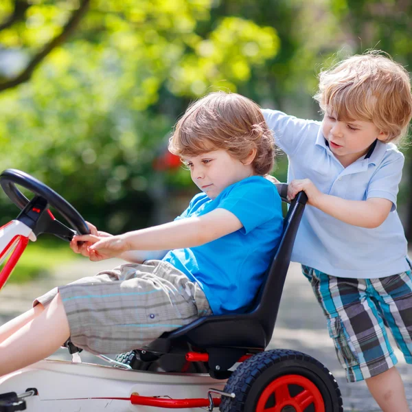 Dos niños felices hermanos divirtiéndose con coche de juguete — Foto de Stock