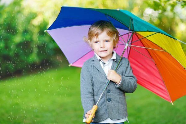 Lilla söta barn pojke med färgglada paraply och stövlar, utomhu — Stockfoto