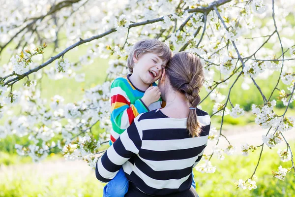 Jovem mãe e menino no jardim florido — Fotografia de Stock
