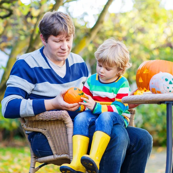 Litet barn och hans far gör jack-o-lantern för halloween — Stockfoto