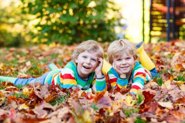 İki küçük renkli giyim sonbahar yaprakları döşeme çocuklar çocuk