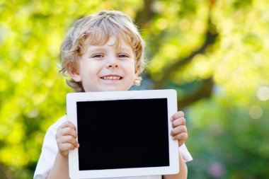 tablet pc, açık havada tutan gülümseyerek mutlu küçük çocuk