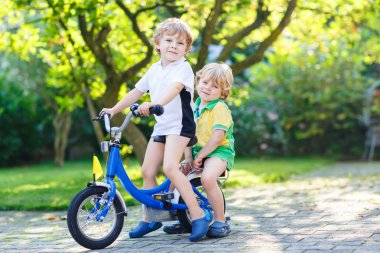 Two little kid boys riding with bicycle together