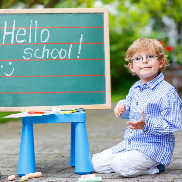 Söt liten unge pojke med glasögon på blackboard öva writin — Stockfoto