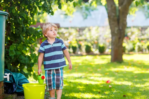 Menino pequeno se divertindo com água espirrando no verão gar — Fotografia de Stock