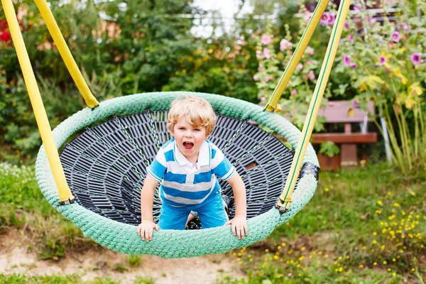 Adorável criança menino ter divertido cadeia swing no playgroun ao ar livre — Fotografia de Stock