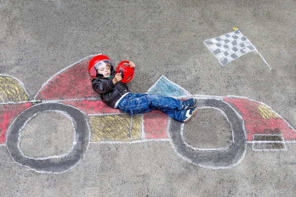 Ragazzino divertirsi con auto da corsa disegno con gessetti — Foto Stock