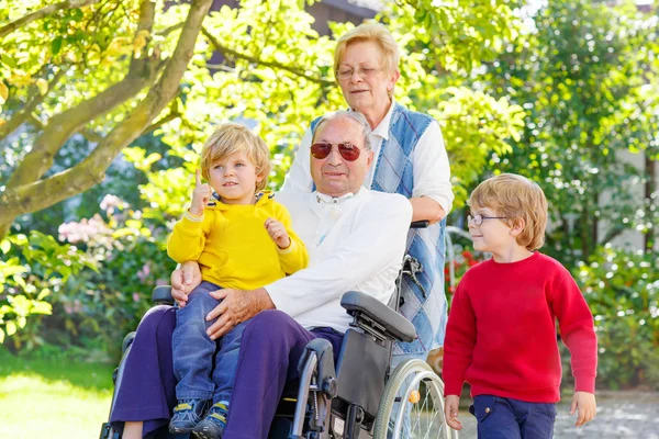 Two little kid boys, their grandmother and grandfather in wheelc — Stock Photo, Image