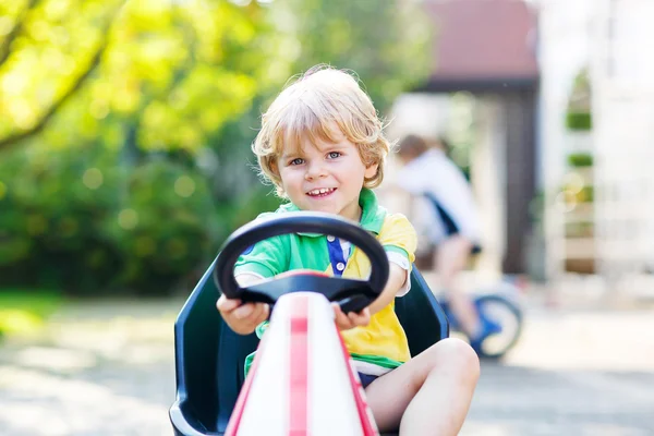 Little kid boy driving pedal car in summer garden — Φωτογραφία Αρχείου
