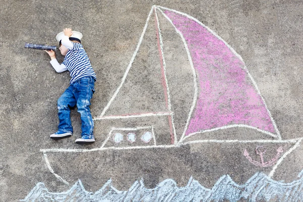 Kleine jongen met plezier met schip afbeelding tekenen met krijt — Stockfoto