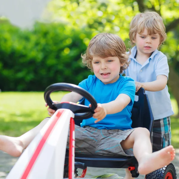 Zwei lustige kleine Jungen haben Spaß mit Rennwagen im Freien — Stockfoto