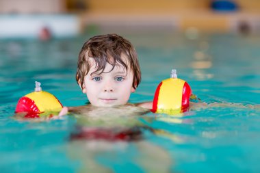 küçük çocuk çocuk swimmies bir kapalı havuzda yüzmek için öğrenme ile