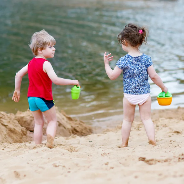 Little toddler boy and girl playing together with sand toys near — Stock Photo, Image