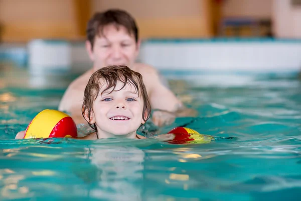 Jonge vader onderwijs zijn zoontje te zwemmen binnenshuis — Stockfoto