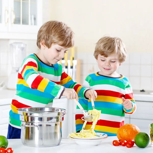 Zwei kleine Jungen essen Spaghetti in der heimischen Küche. — Stockfoto