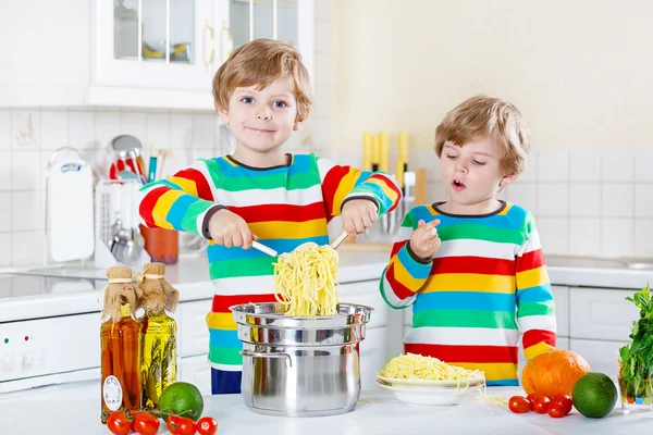 Dwa małe dziecko chłopców jedzenie spaghetti w domowej kuchni. — Zdjęcie stockowe