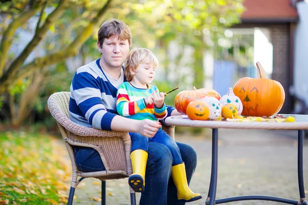 Litet barn och hans far gör jack-o-lantern för halloween — Stockfoto
