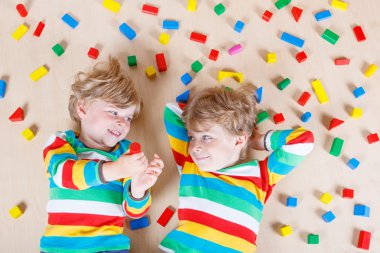 Two little children playing with colorful wooden blocks indoor