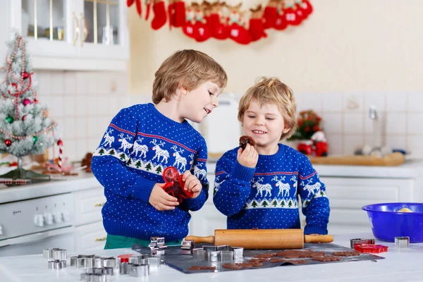 Два маленьких мальчика пекут пряничное печенье на домашней кухне — стоковое фото